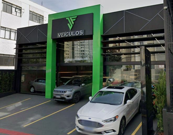 Fachada de uma loja de veículos com carros expostos na entrada